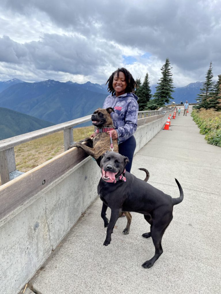 Woman smiles with her two dogs on an overlook