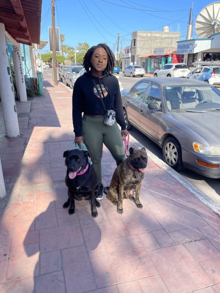 Woman poses with her two dogs on the sidewalk