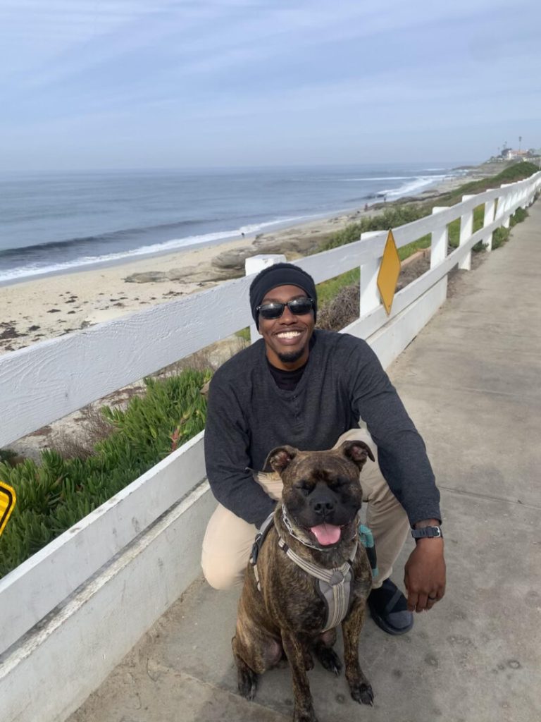 Man poses with his dog near the beach